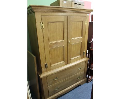A LIGHT OAK CUPBOARD with twin doors above two drawers and raised on bracket feet, 97cm wide x 63cm deep x 150cm high