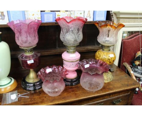 A GROUP OF THREE OLD OIL LAMPS to include one with a Cranberry glass reservoir and with two further oil lamp shades (5) 