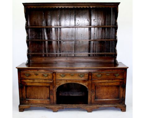 AN ANTIQUE ELM DRESSER BASE  with three long drawers above two panel doors and raised on bracket feet, having a later plate r