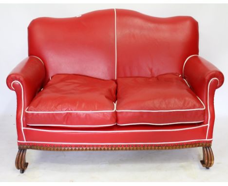 A RED LEATHER TWO SEATER SOFA with shaped back, 126cm x 88cm approximately