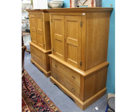 A PAIR OF LIGHT OAK CUPBOARDS each with twin doors above two drawers, raised on bracket feet, 101cm wide x 60cm deep x 150cm 