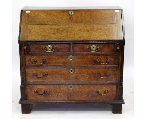 AN 18TH CENTURY OAK BUREAU the fall front opening to reveal drawers and pigeon holes, above two short and three long drawers,