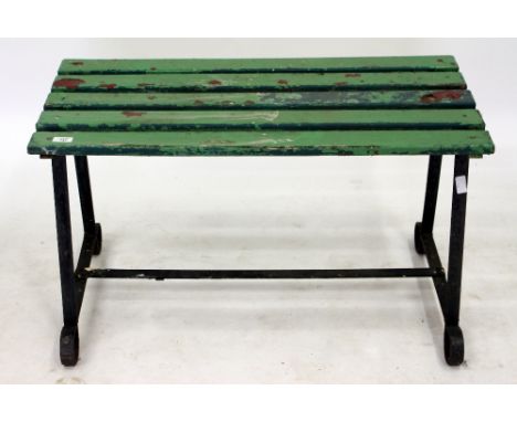 AN OLD WROUGHT IRON GARDEN BENCH OR TABLE with green painted wooden slats to the top, 91cm wide x 54cm high