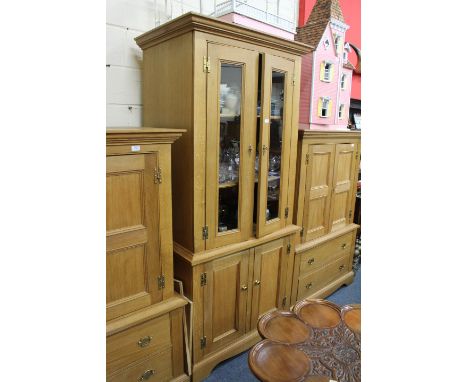 A LIGHT OAK CUPBOARD with twin glazed doors above twin panelled doors, raised on bracket feet, 94cm wide x 65cm deep x 204cm 