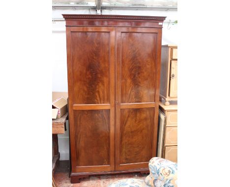 A VICTORIAN MAHOGANY WARDROBE  with twin panelled doors and raised on bracket feet, 110cm x 57cm x 196cm