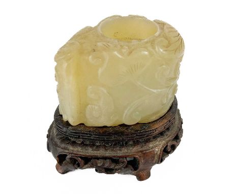 A Chinese mutton fat jade brush pot, 19th century Carved with foliage, on a carved hardwood stand, height of pot 3.5cm, width
