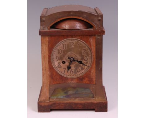 An Art Nouveau oak and brass bound mantel clock in the Glasgow School style, having stylised circle embossed dial, twin windi