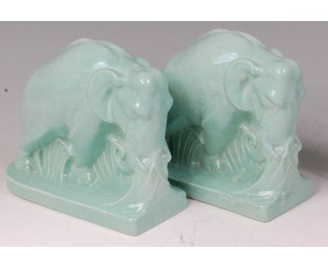 A pair of Art Deco Poole Pottery elephant form book-ends, each in rutting pose within foliage, underglaze painted in pale gre