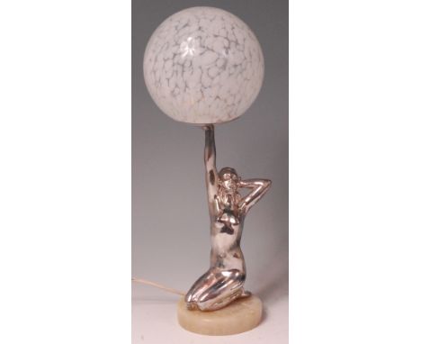 An Art Deco chrome table lamp in the form of a female kneeling nude, holding aloft a mottled globular glass shade, raised on 