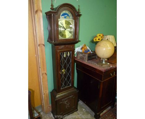 A contemporary Oak longcase Clock, the face with Roman numerals having moon phases to the arch, the pendulum and weights visi