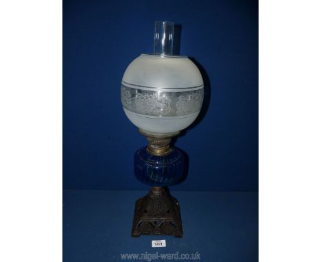 An oil lamp with blue glass reservoir and cast metal base, globe shade and chimney, 22'' tall.