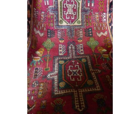 A Persian style wool runner with multi-medallion centre upon a red field, with further abstract detail, within running border