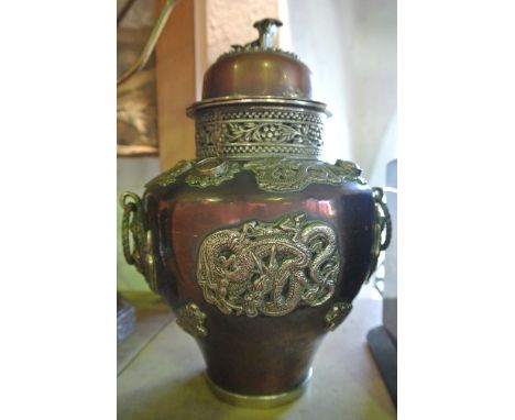 An eastern lidded vessel of baluster form with extensive applied white metal decoration in the form of dragons, etc, the shou