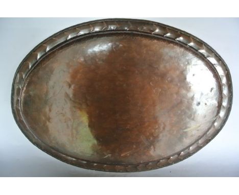 A beaten copper tray of oval form, the raised border with inter-cut sectional white metal inlay and further shaped detail in 