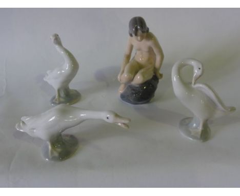 A Royal Copenhagen ceramic model of  a seated female nude, 14 cm tall approx together with three Lladro models of swans