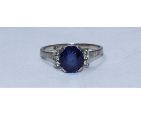 An 18ct white gold and platinum ring, centrally claw-set an oval faceted sapphire, 9.20mm x 8.10mm flanked each side by three