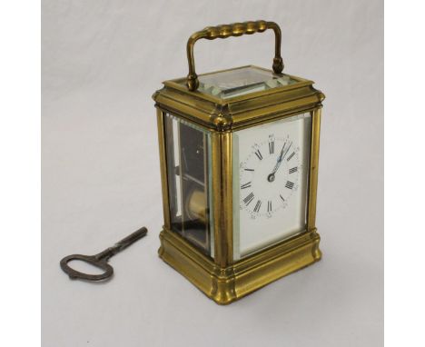 A French brass carriage clock by Henri Jacot, the exposed platform escapement above a white enamel dial with Roman and Arabic