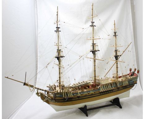 A hand-built scale wooden model of an 18th century fully-rigged three-masted ship, with 8-guns, wooden tender, white-painted 