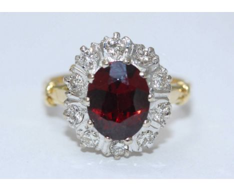 An 18ct yellow gold diamond and ruby ring, centrally set with a synthetic oval faceted ruby 10.04 x 7.96mm, surrounded in rho