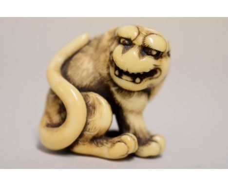 A good Japanese carved ivory netsuke of a tiger or monkey, Kyoto School, probably Edo, signed, finely carved and with inset e