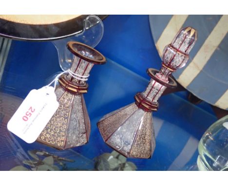 A PAIR OF VICTORIAN GLASS SCENT BOTTLES with ruby and gilt overlaid decoration (one stopper missing)