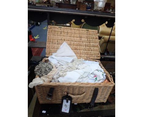 A WICKER PICNIC HAMPER containing Vintage mats, table cloths and textiles