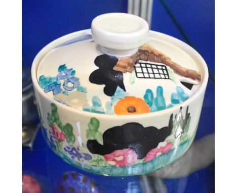 CLARICE CLIFF: A SQUAT LIDDED POT decorated with a cottage and flowers, 10.5cm dia.