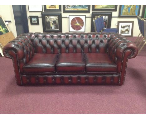 THREE SEAT BUTTON BACK CHESTERFIELD STYLE SOFAupholstered in ox blood red leather, with detachable seat cushions, 197 cm wide