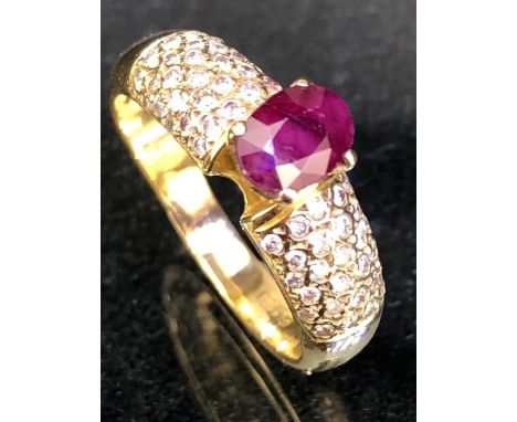 Foreign Gold ring set with a Red faceted stone possibly a Ceylon Ruby in a four clasp mount and with many small diamonds to e