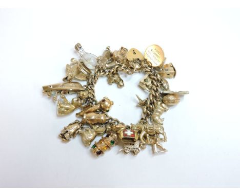 A 9ct gold curb link chain bracelet, with thirty-one assorted charms attached, three charms tested as approximately 18ct gold