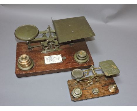 Two pairs of brass and oak letter scales and weights, the larger with inland letter rates plaque