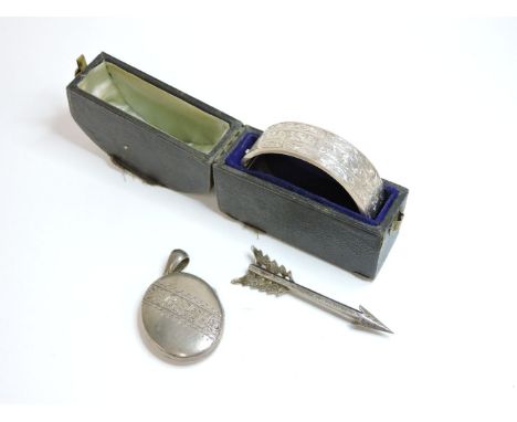 A silver bangle, a silver locket, and an arrow brooch