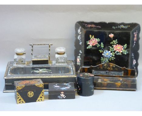 A Victorian papier mâché desk stand, with a lidded stamp box, two glass inkwells, and a fold out writing slope, decorated wit