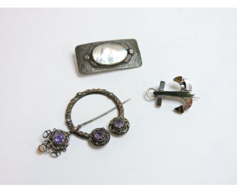 An Arts and Crafts mother of pearl brooch, marked 'Dawn Reg'd', an Arts and Crafts Amy silver penanular brooch, and a hardsto