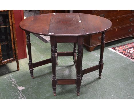 A mahogany dropleaf dining table with turned supports and ceramic casters