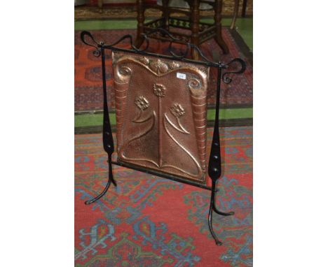 An Art Nouveau beaten copper and wrought iron firescreen, the rectangular banner embossed with flowers on sinuous whiplash st