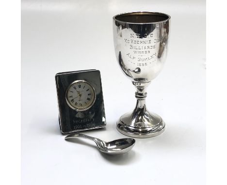 A silver trophy cup, a silver caddy spoon and a silver mounted timepiece.