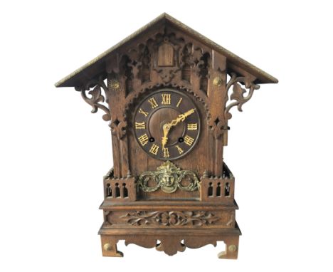 A black forest oak cuckoo mantel clock, late 19th century, with arched top and blind pierced Gothic tracery, applied brass ma