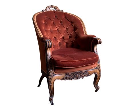 A carved walnut buttoned armchair.From the estate of Ashley Barker OBE who was born in Hertfordshire in 1927.Being unusually 