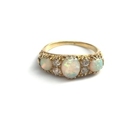 A late Victorian gold ring set with 3 opals, these separated by pairs of diamonds, chased claw settings. 