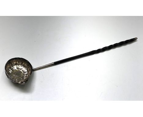 An 18th century silver punch ladle with embossed floral panels an inset Queen Anne shilling dated 1709, twisted baleen handle