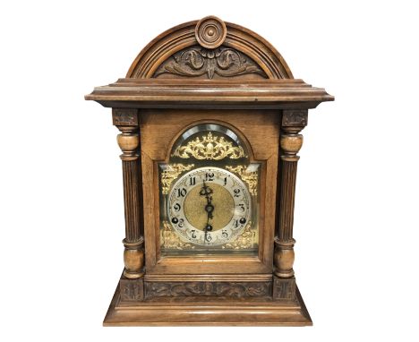 A late 19th century Württemberg mantle clock, in a carved hardwood case, the enamel dial with black numerals on a decorative 