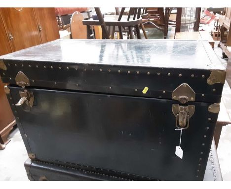 Old brass bound trunk with leather carrying handles, 84cm wide, 48cm deep, 52cm high, containing cushions and old rugs