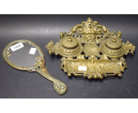 A cast brass desk standish with two inkwells, mask design; an Art Nouveau style hand mirror (2)