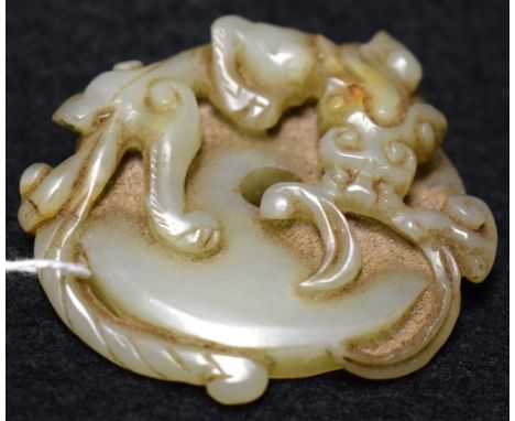 A Chinese jade roundel, carved as an ensnaring mythical beast, 5.5cm diam 