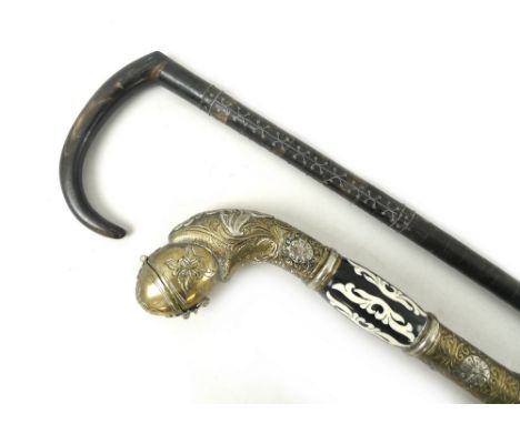 An ebonised walking cane, with brass and white metal handle formed as a snake eating an egg, with hinged end, 98cm, together 