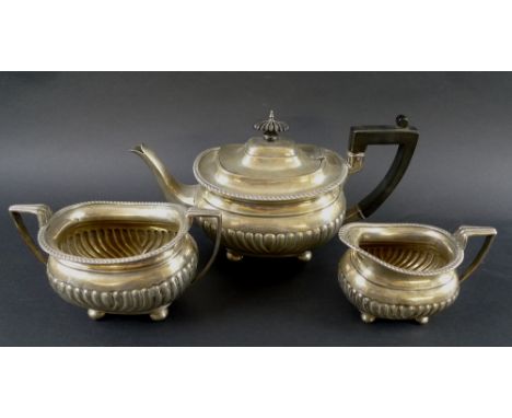 An Edward VII silver three piece tea service, comprising teapot, milk jug and twin handled sugar bowl, boat shaped bodies wit