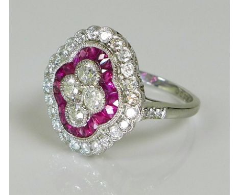 An 18ct white gold, diamond and ruby dress ring of unique design, set with four central diamonds in a quatrefoil, bordered wi