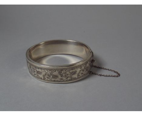 A Wax Filled Silver Bangle with Etched Foliate Decoration and Safety Chain.