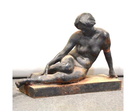 Cast iron garden sculpture of a resting female nude, painted in black, weathered and with some losses, on a rectangular plint